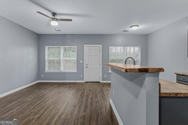 interior space with dark wood-style floors, baseboards, visible vents, and a ceiling fan