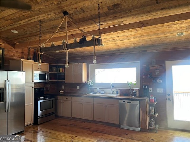 kitchen featuring decorative light fixtures, wood-type flooring, appliances with stainless steel finishes, a sink, and wooden ceiling