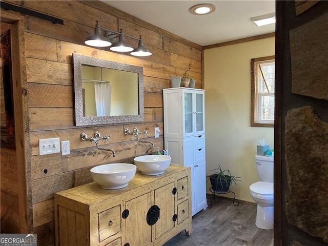 bathroom with double vanity, a sink, toilet, and wood finished floors