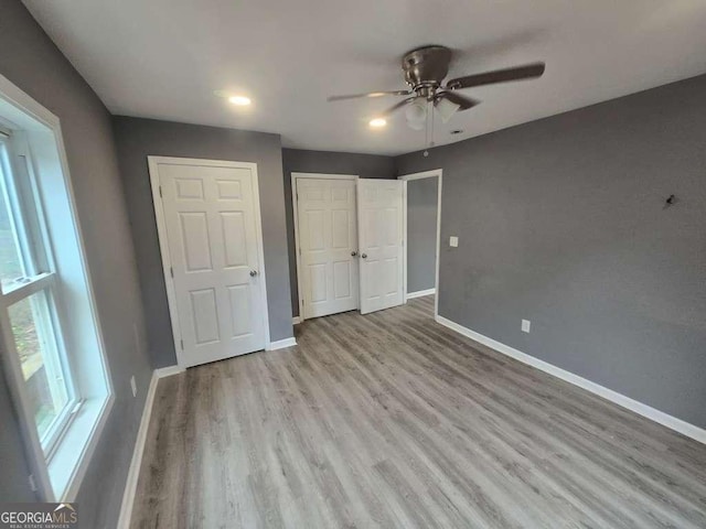 unfurnished bedroom featuring a closet, ceiling fan, baseboards, and wood finished floors