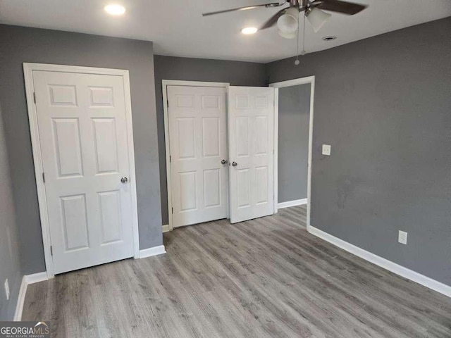 unfurnished bedroom with ceiling fan, a closet, wood finished floors, and baseboards