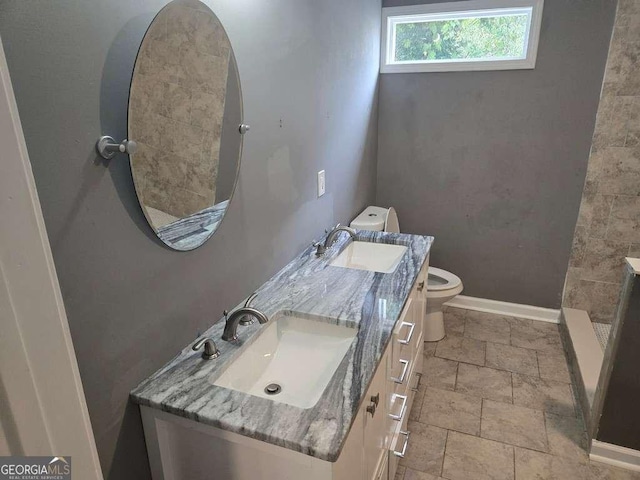 bathroom with double vanity, baseboards, toilet, and a sink