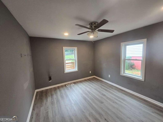 spare room with a ceiling fan, baseboards, visible vents, and wood finished floors