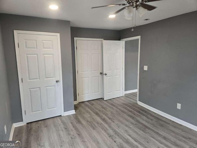 unfurnished bedroom featuring a ceiling fan, a closet, baseboards, and wood finished floors