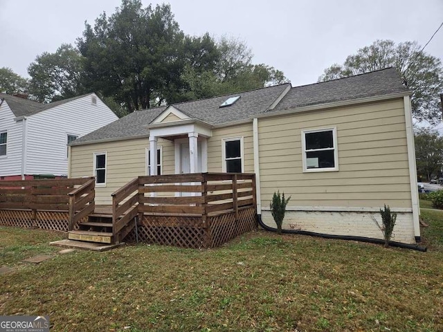 back of property featuring a deck, a yard, and roof with shingles