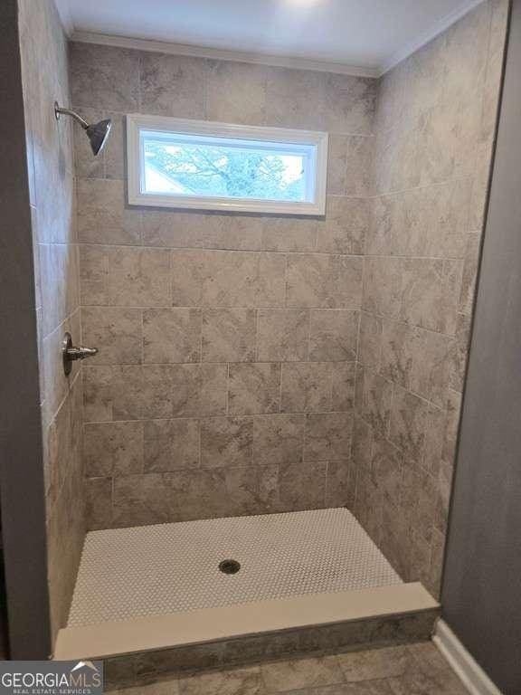 full bath featuring tiled shower and crown molding