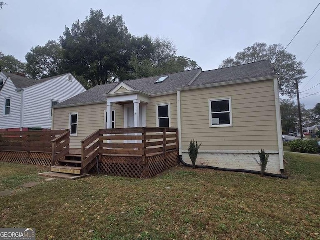 back of property featuring roof with shingles, a yard, and a wooden deck