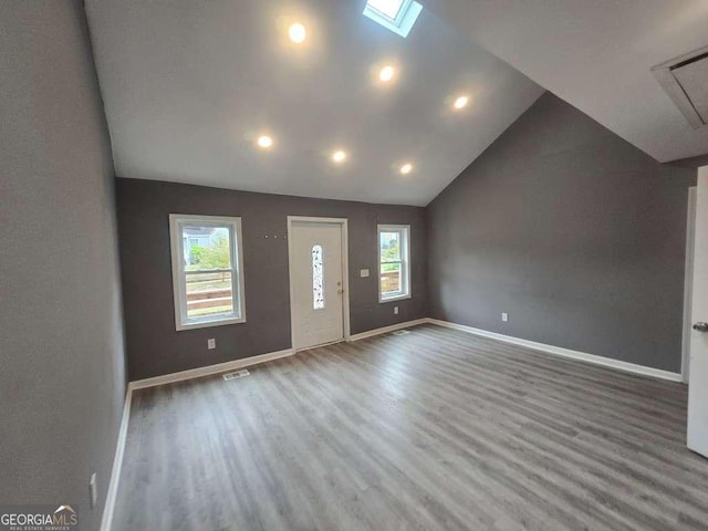 foyer entrance with vaulted ceiling with skylight, recessed lighting, wood finished floors, visible vents, and baseboards