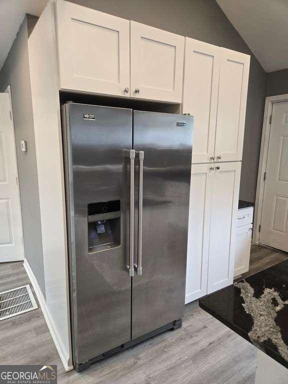 kitchen featuring white cabinets, light wood finished floors, visible vents, and stainless steel refrigerator with ice dispenser