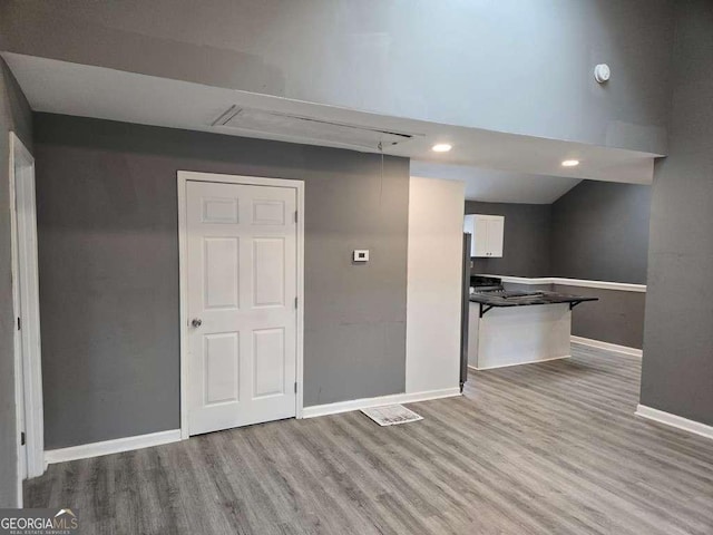 interior space featuring wood finished floors, white cabinetry, and baseboards