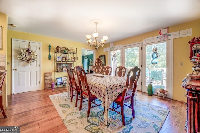 dining room with light wood-type flooring and an inviting chandelier