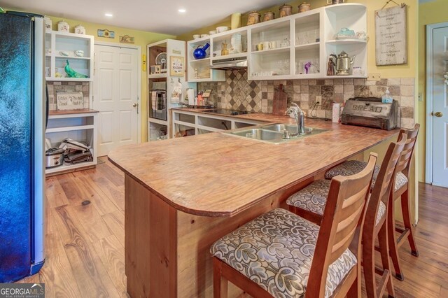 kitchen featuring light wood-style flooring, appliances with stainless steel finishes, open shelves, and a sink