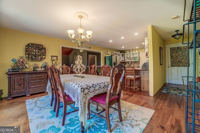 dining space featuring recessed lighting, an inviting chandelier, and wood finished floors