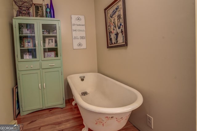 bathroom with a freestanding tub and wood finished floors