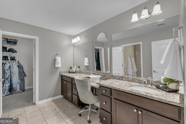 full bathroom with double vanity, a spacious closet, visible vents, and a sink