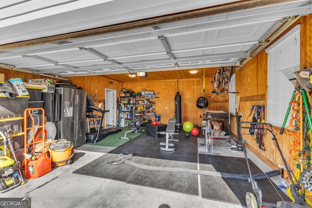 garage featuring wooden walls and stainless steel fridge with ice dispenser