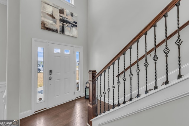 entrance foyer with a towering ceiling, stairs, and dark wood-type flooring