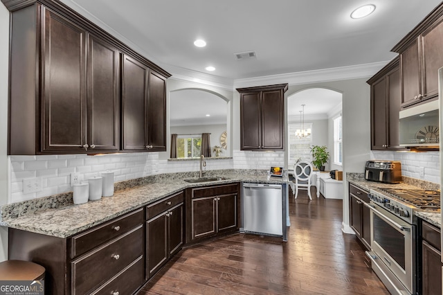 kitchen with stainless steel appliances, dark brown cabinets, a sink, and dark wood finished floors