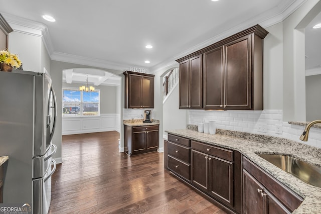 kitchen featuring dark wood-type flooring, a sink, dark brown cabinets, freestanding refrigerator, and decorative backsplash