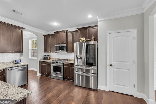 kitchen with light stone counters, stainless steel appliances, dark wood-type flooring, visible vents, and dark brown cabinets