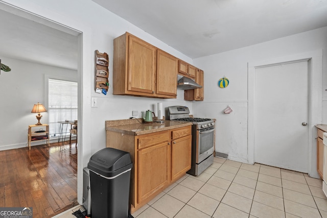 kitchen featuring stainless steel gas stove, brown cabinetry, and under cabinet range hood