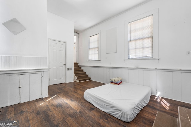 bedroom featuring a wainscoted wall, wood-type flooring, and visible vents