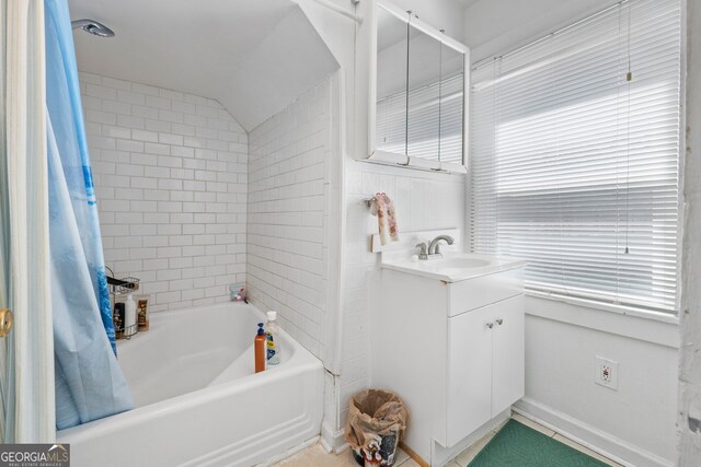 bathroom with lofted ceiling, shower / bath combo with shower curtain, and vanity