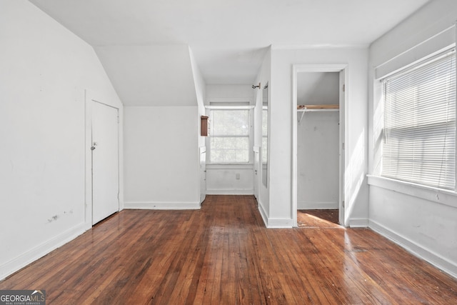 unfurnished bedroom with lofted ceiling, a closet, baseboards, and hardwood / wood-style floors