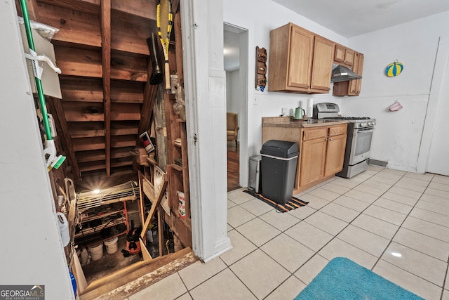 kitchen featuring light tile patterned floors, under cabinet range hood, and gas range