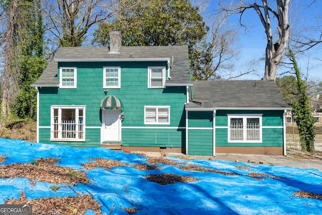 view of front of house featuring roof with shingles and a chimney