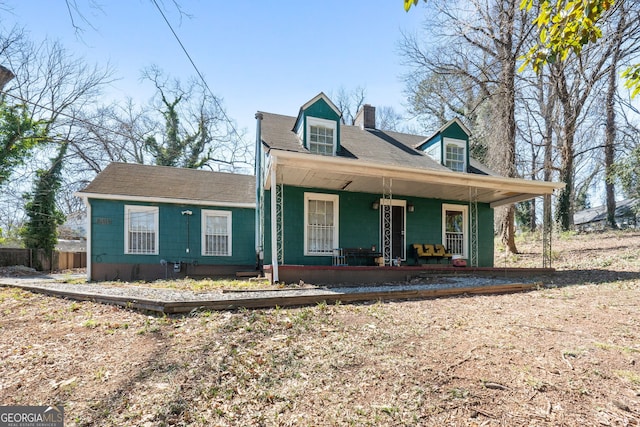 view of front of house featuring a porch, a chimney, and fence