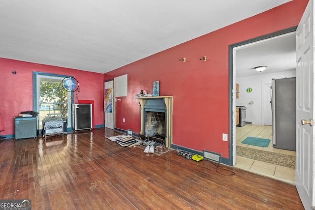 living room with wood-type flooring, visible vents, baseboards, and a stone fireplace