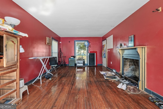 living area with hardwood / wood-style floors, a fireplace with flush hearth, visible vents, and baseboards