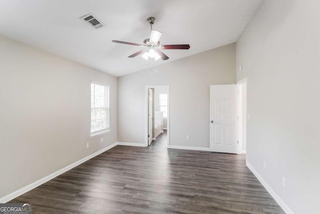 spare room featuring baseboards, visible vents, a ceiling fan, lofted ceiling, and dark wood-style floors