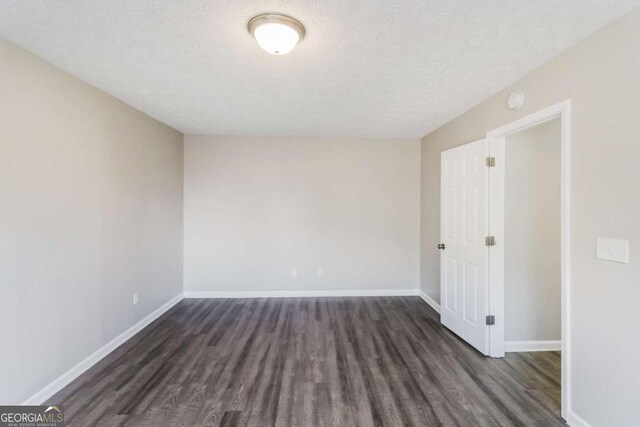 spare room with a textured ceiling, baseboards, and wood finished floors