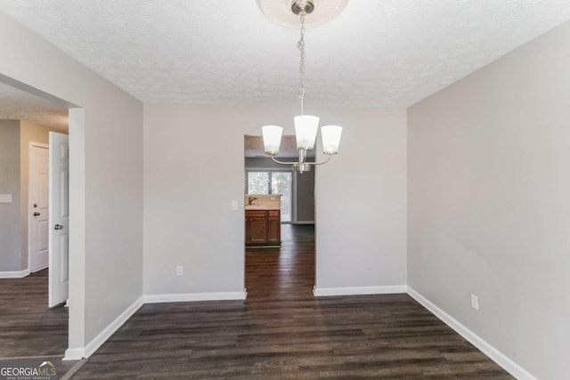 unfurnished dining area with a textured ceiling, baseboards, and wood finished floors