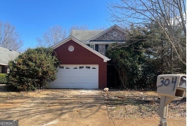 traditional-style home featuring a garage, brick siding, and driveway