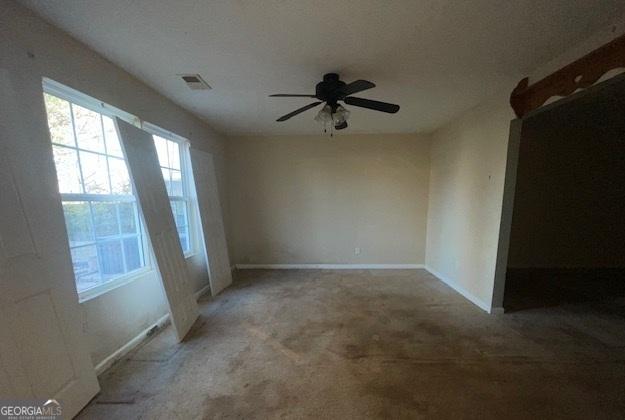 carpeted empty room with baseboards, a textured ceiling, visible vents, and a ceiling fan