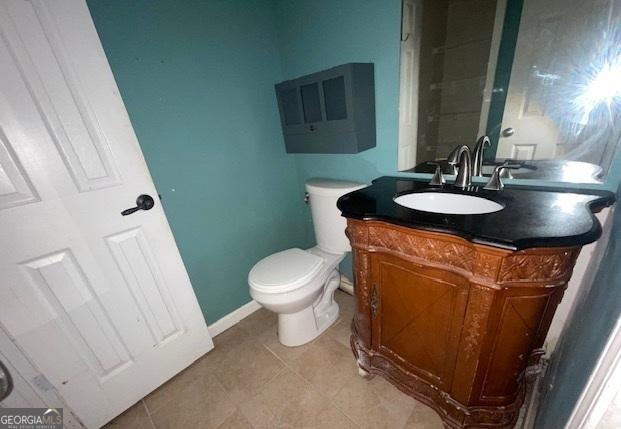 bathroom featuring toilet, tile patterned floors, baseboards, and vanity