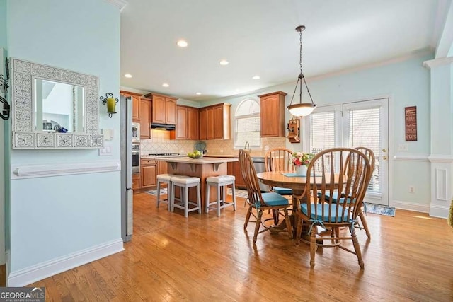 dining area with light wood-style flooring, baseboards, crown molding, and recessed lighting