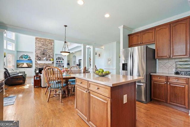 kitchen featuring light wood-type flooring, open floor plan, a fireplace, and stainless steel fridge with ice dispenser