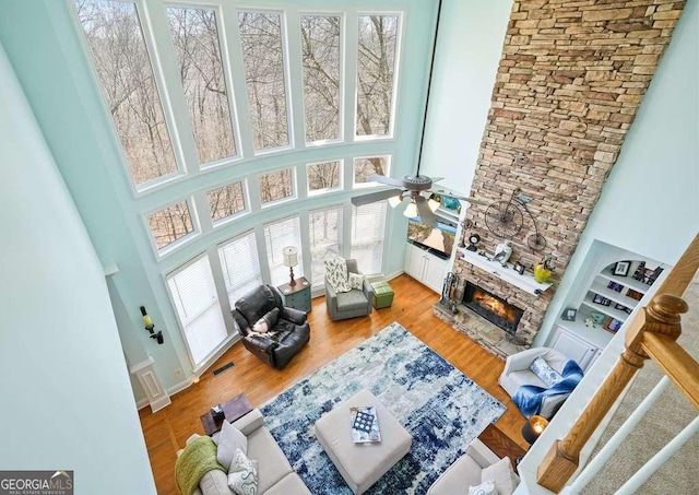 living room featuring light wood-type flooring, visible vents, a fireplace, and a towering ceiling