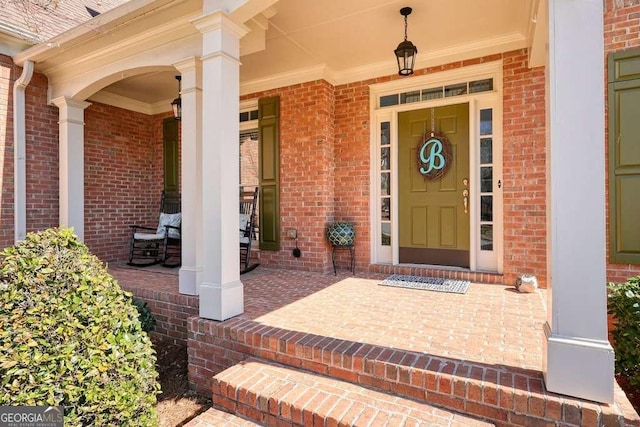 doorway to property with covered porch and brick siding