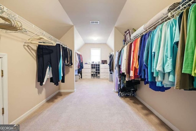 spacious closet featuring lofted ceiling, carpet floors, and visible vents