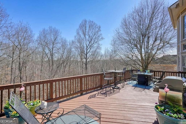 wooden terrace with a grill and outdoor dining area