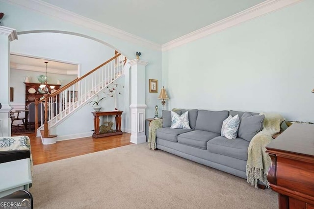 carpeted living area with ornate columns, stairs, a chandelier, and crown molding