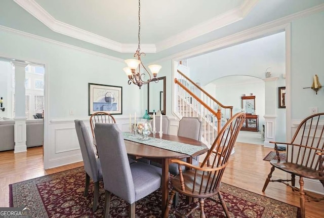 dining room featuring wainscoting, decorative columns, and light wood finished floors