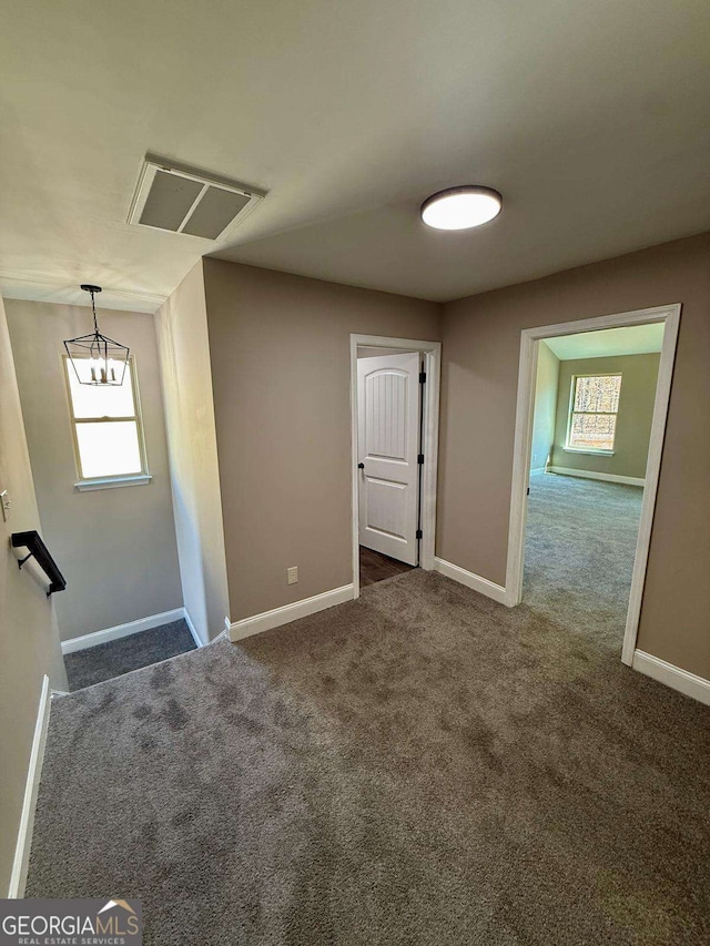 unfurnished room featuring visible vents, dark carpet, and baseboards