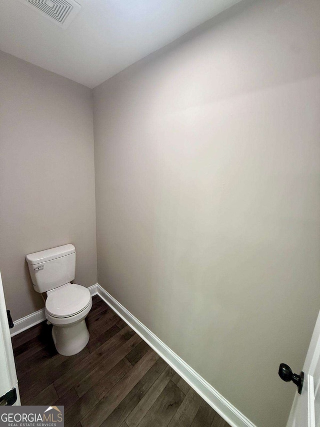 bathroom featuring baseboards, visible vents, toilet, and wood finished floors