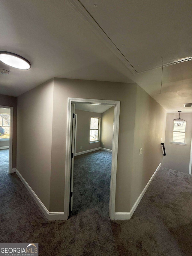 hall featuring attic access, baseboards, and carpet flooring